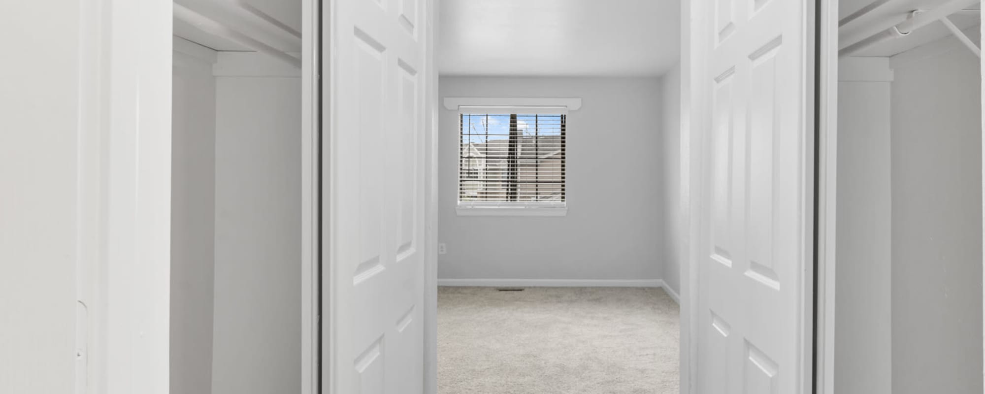 View into a bedroom with a window and two closets with sliding doors at Eagle's Edge in Indianapolis 