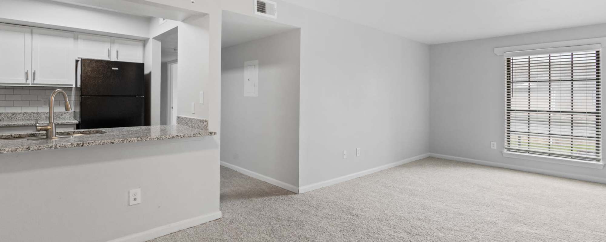 Wide open living room space with a large window and view of the kitchen at Eagle's Edge in Indianapolis 