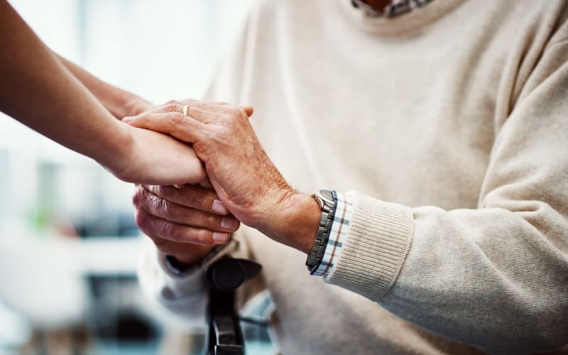 Caregiver holding her father's hands at Grand Villa of Clearwater in Clearwater, Florida