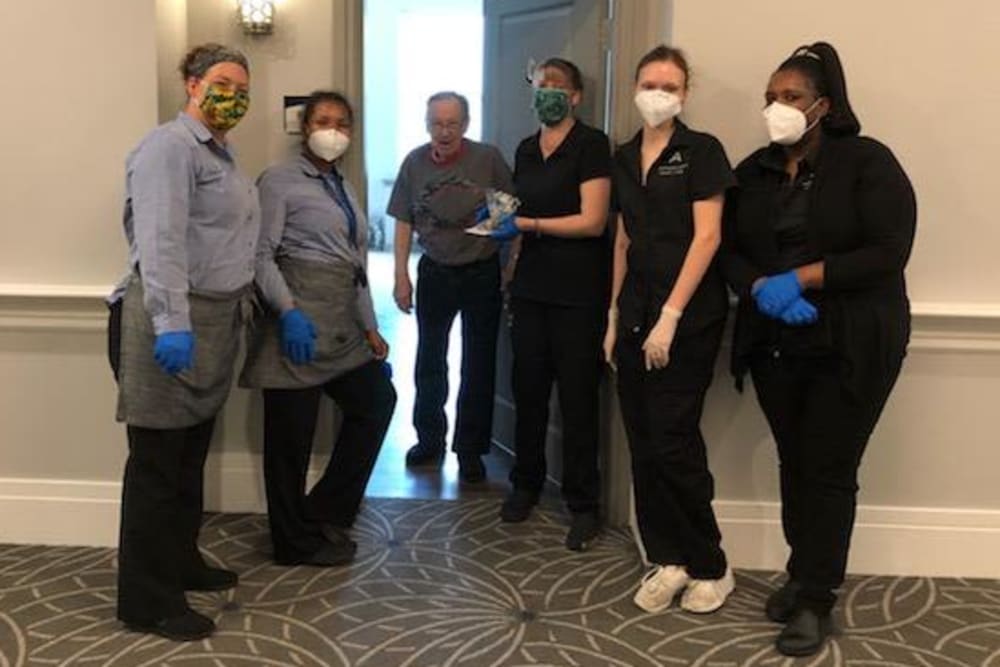 Group of masked caretakers greeting a resident at their door at a Anthology of Millis community