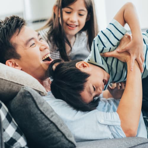 A father and his children playing on a couch in a home at Silver Strand I in Coronado, California