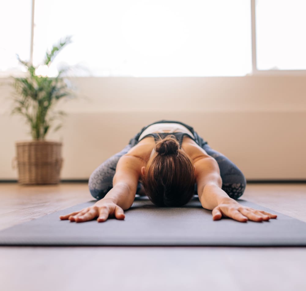 Resident stretching on a yoga mat in the onsite fitness center at Haven Apartment Homes in Kent, Washington