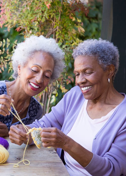 Two elderly women smiling while knitting at The Pillars of Grand Rapids in Grand Rapids, Minnesota