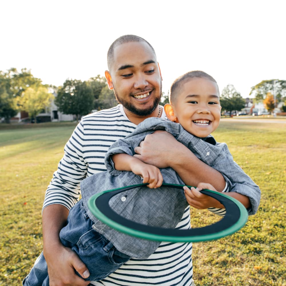 Resident playing with his son in a park near Mapleton Square Apartment Homes in Dover, Delaware