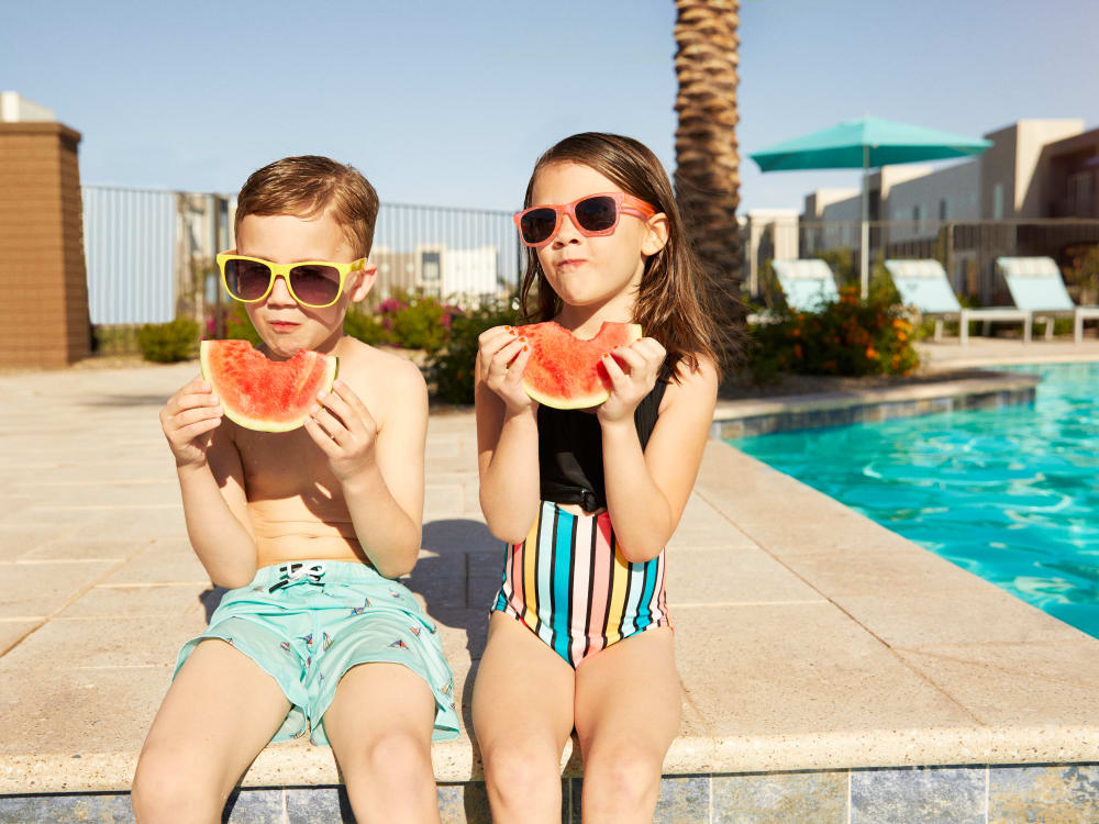Two young residents eating watermelon by the pool at BB Living at Val Vista in Gilbert, Arizona