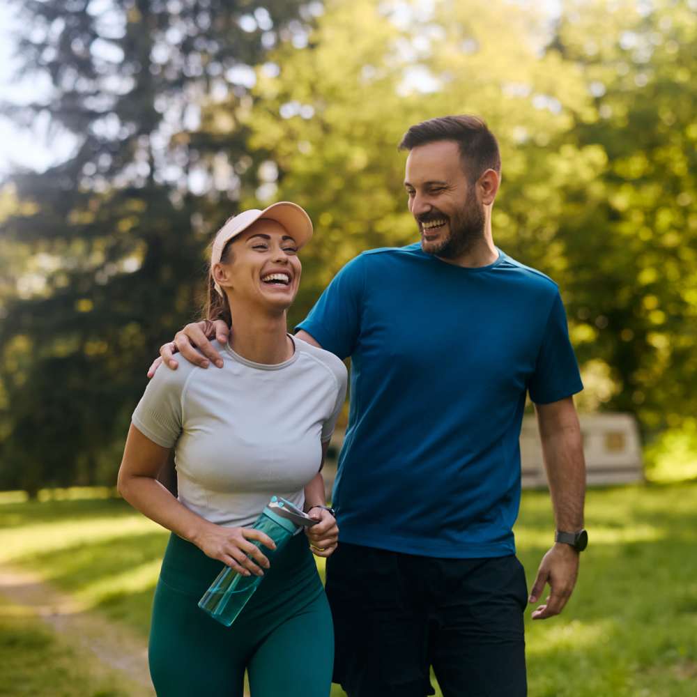 Two people laughing while walking in a park at Avia Lofts at Maple Road in Amherst, New York