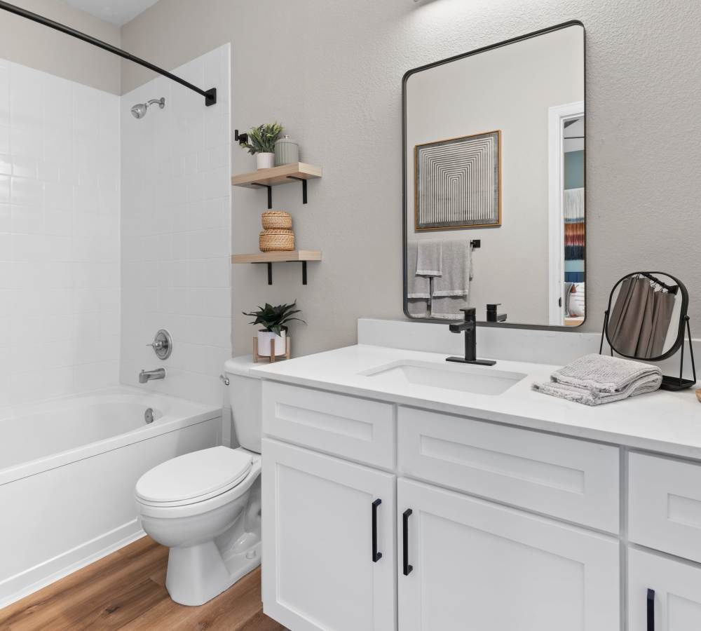 Bathroom with white cabinets, stone counters, and wood-style flooring