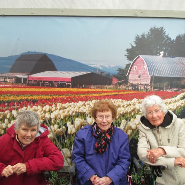 3 women standing in front of a mural of tulips at Quail Park Memory Care Residences of West Seattle in Seattle, Washington