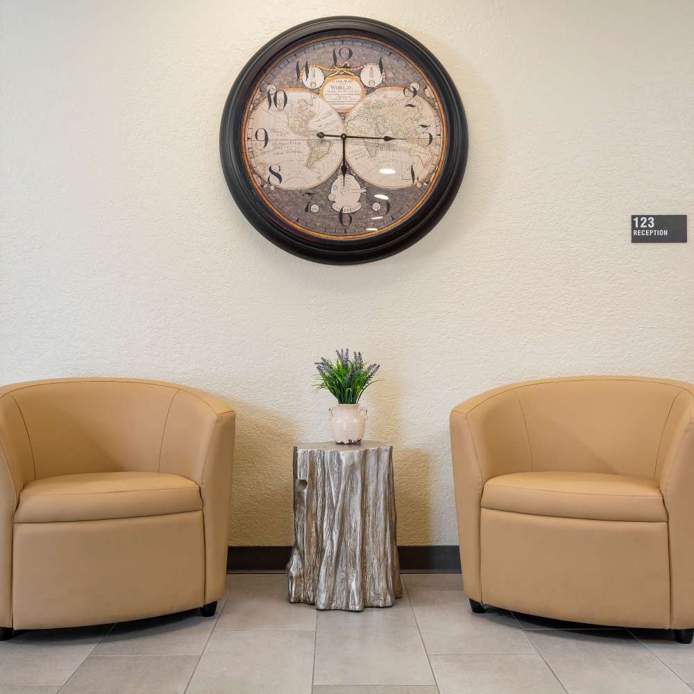 Two seat lounge area with soft eating and a large clock above at Casa Panorama in Panorama City, California