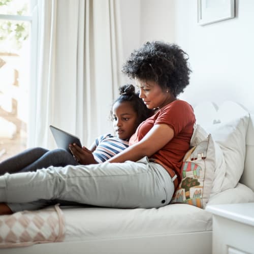 A mother and daughter looking at a tablet in a bedroom at The Village at Whitehurst Farm in Norfolk, Virginia