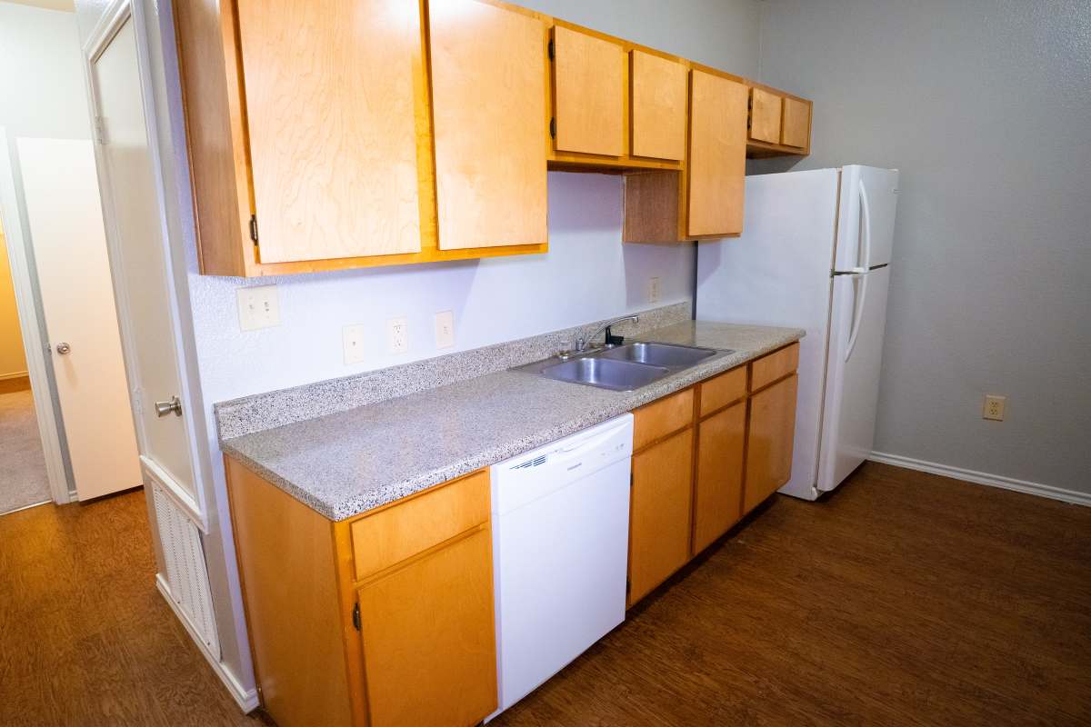 A kitchen showing a dishwasher and a kitchen sink with a refrigerator at Ryan's Crossing in Marshall, Texas