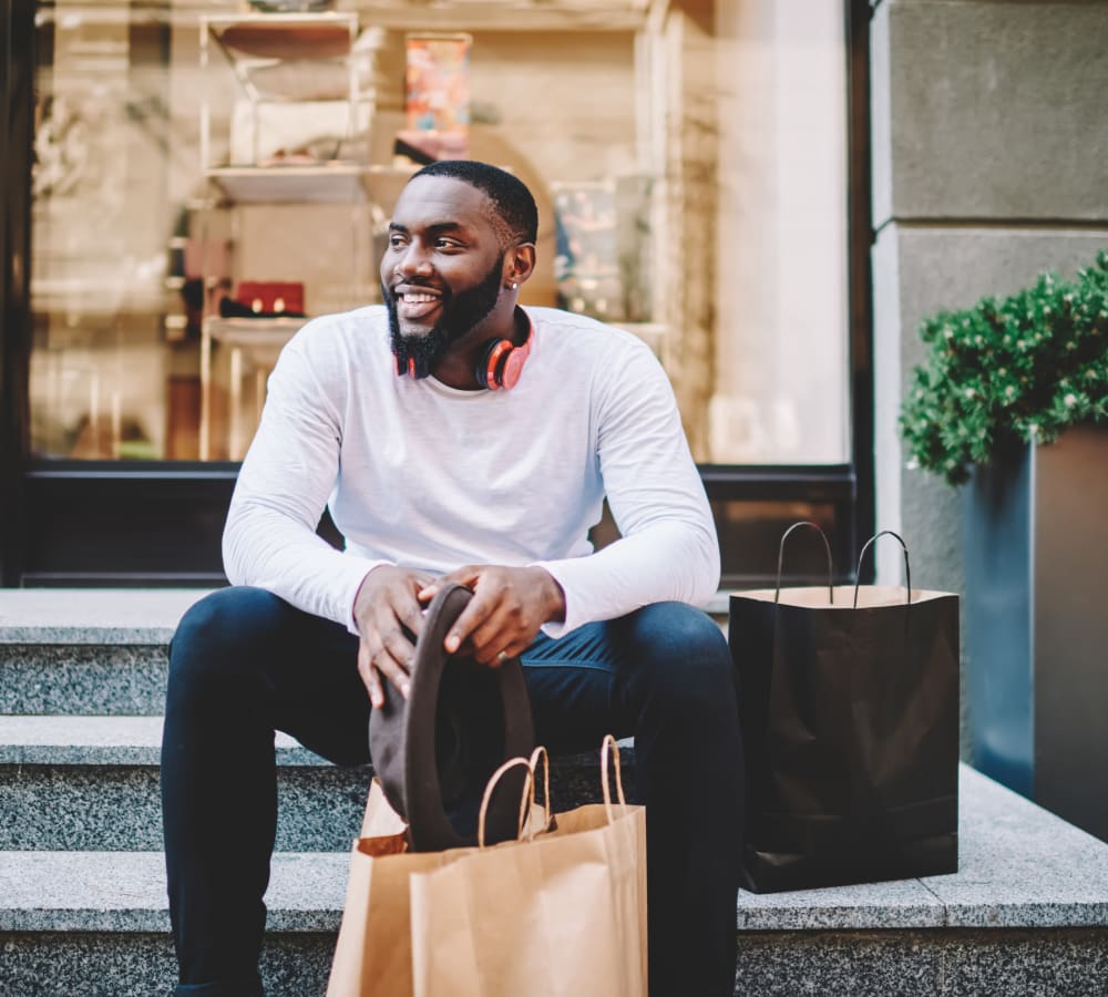 A man with a shopping bag sitting on steps outside of a shop near Chace Lake Villas in Birmingham, Alabama