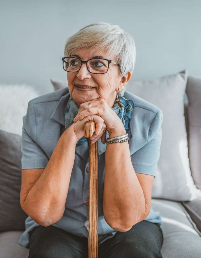 Senior woman sitting on the couch with a cane at Clearwater at Sonoma Hills in Rohnert Park, California
