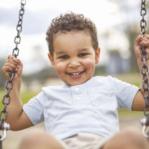 A child smiling while swinging at the playground at Ascent Apartment Homes in Asheville, North Carolina