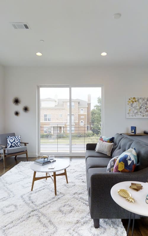 Furnished apartment with large area rug and sliding glass doors to private backyard at The Collection Townhomes in Dallas, Texas