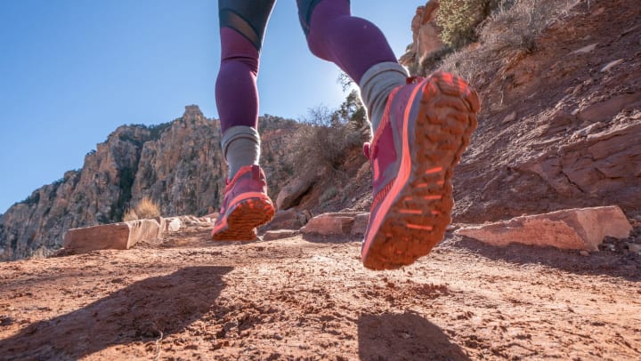  Low-angle photo of woman running along desert terrain