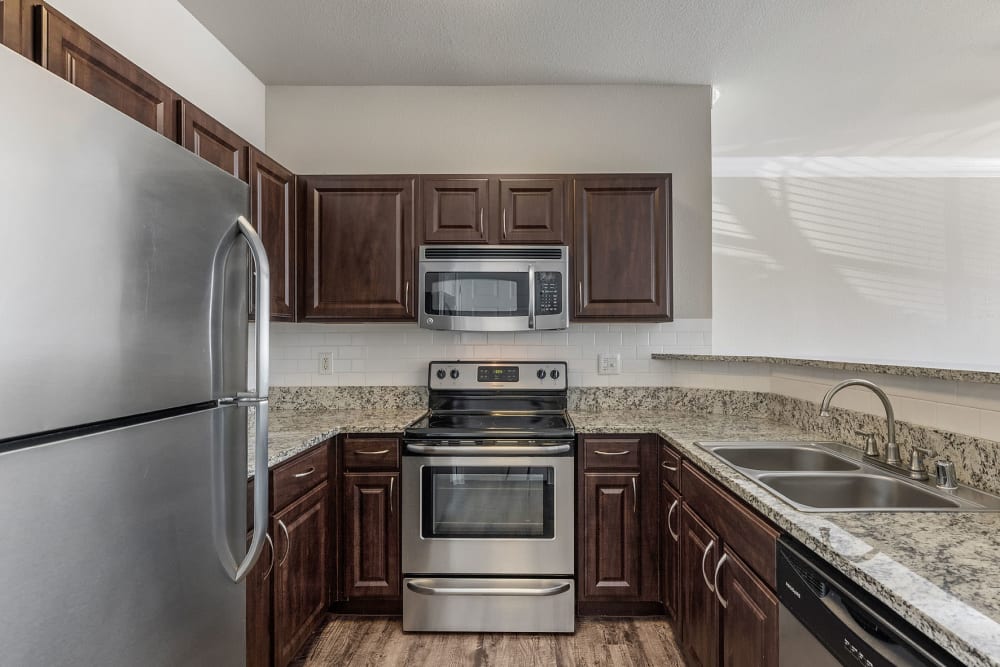 Modern kitchen with stainless steel appliances, granite counter tops, and wood flooring at Marquis at Stonegate in Fort Worth, Texas 