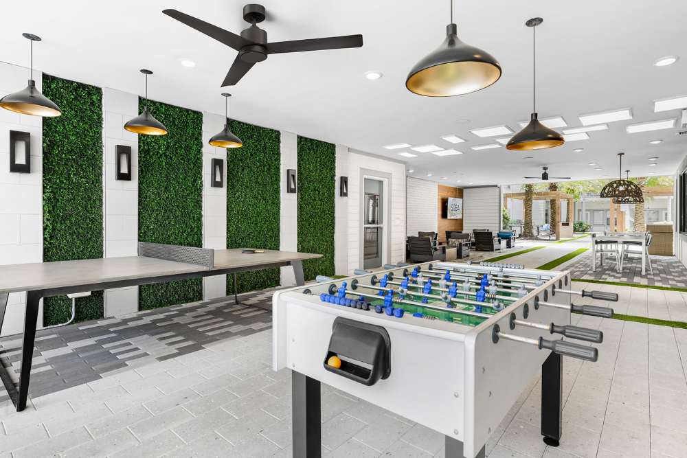 Resident game room with foosball table and hanging light fixtures at SoBA Apartments in Jacksonville, Florida