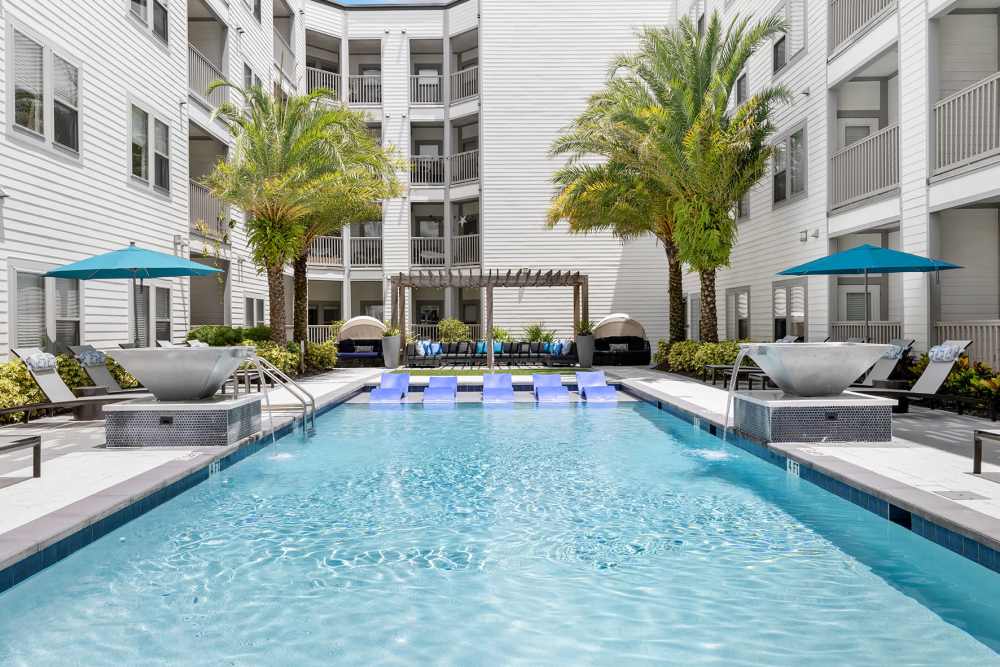 Exterior and pool with seating and umbrellas at SoBA Apartments in Jacksonville, Florida
