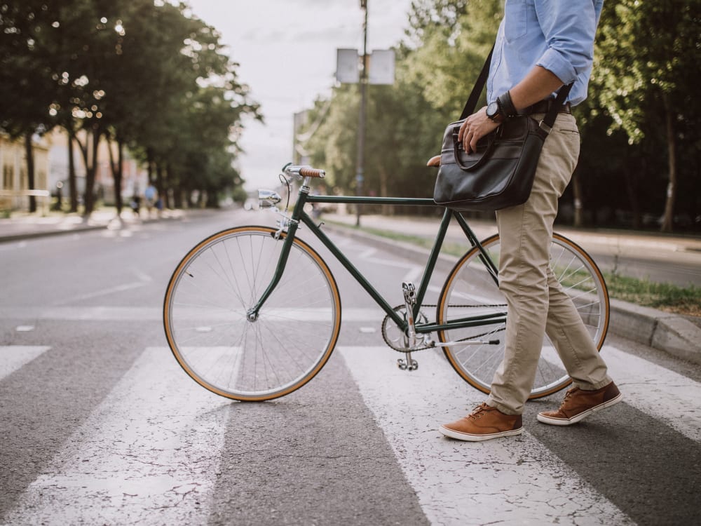 Man walking his bike across a crosswalk on his way to work at Terra Apartment Homes in Federal Way, Washington