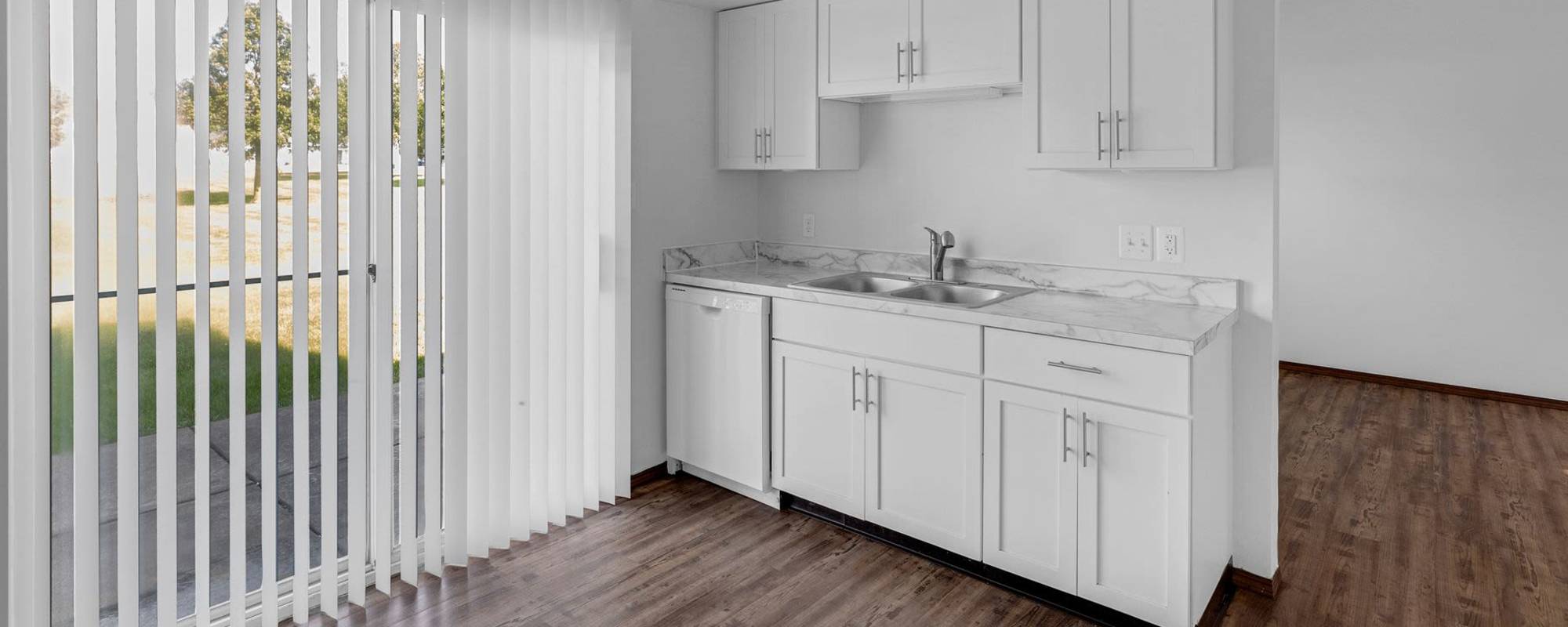 A bright kitchen with white cabinets, refrigerator and stove at Meadowlark Townhomes in Dekalb, Illinois