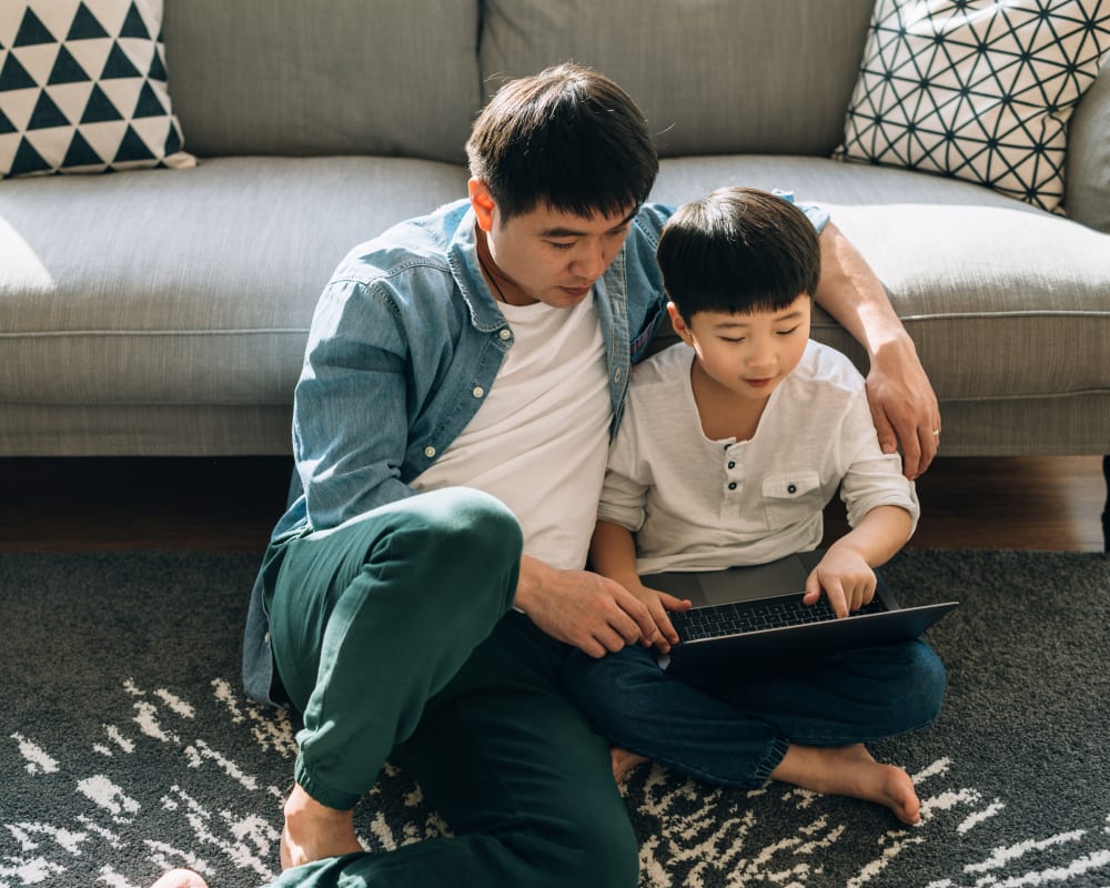 Resident father and son filling out a form on our website on a laptop in their new home at Sofi Canyon Hills in San Diego, California